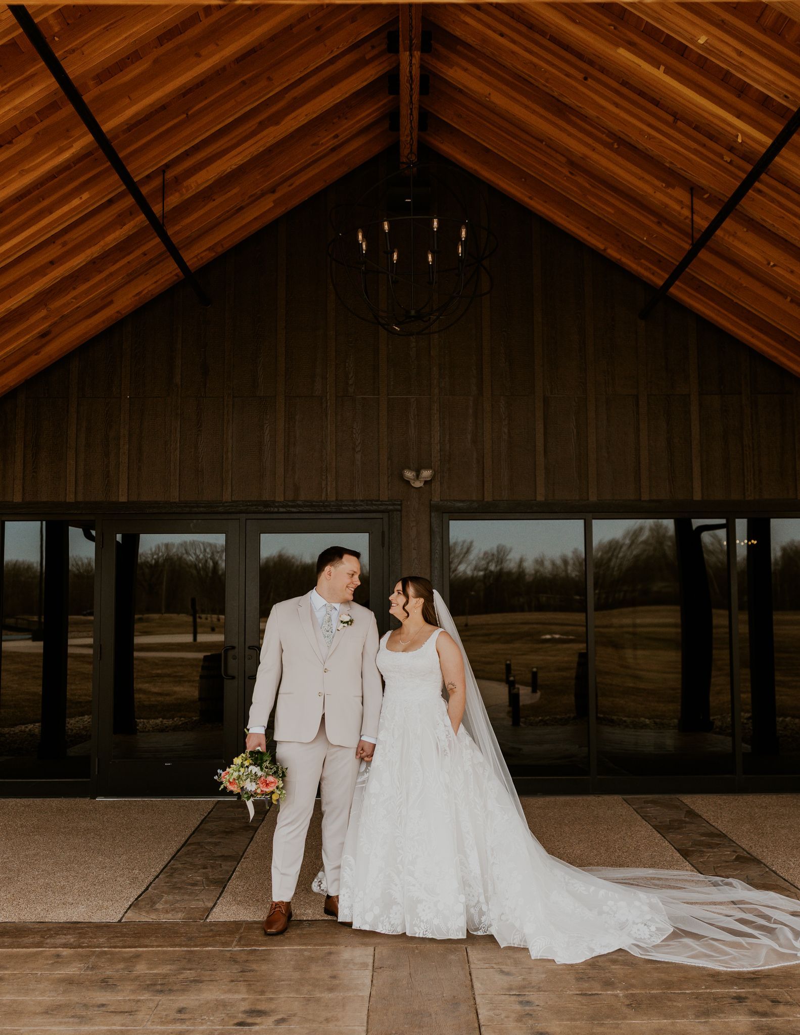 A bride and groom are standing next to each other holding drinks.