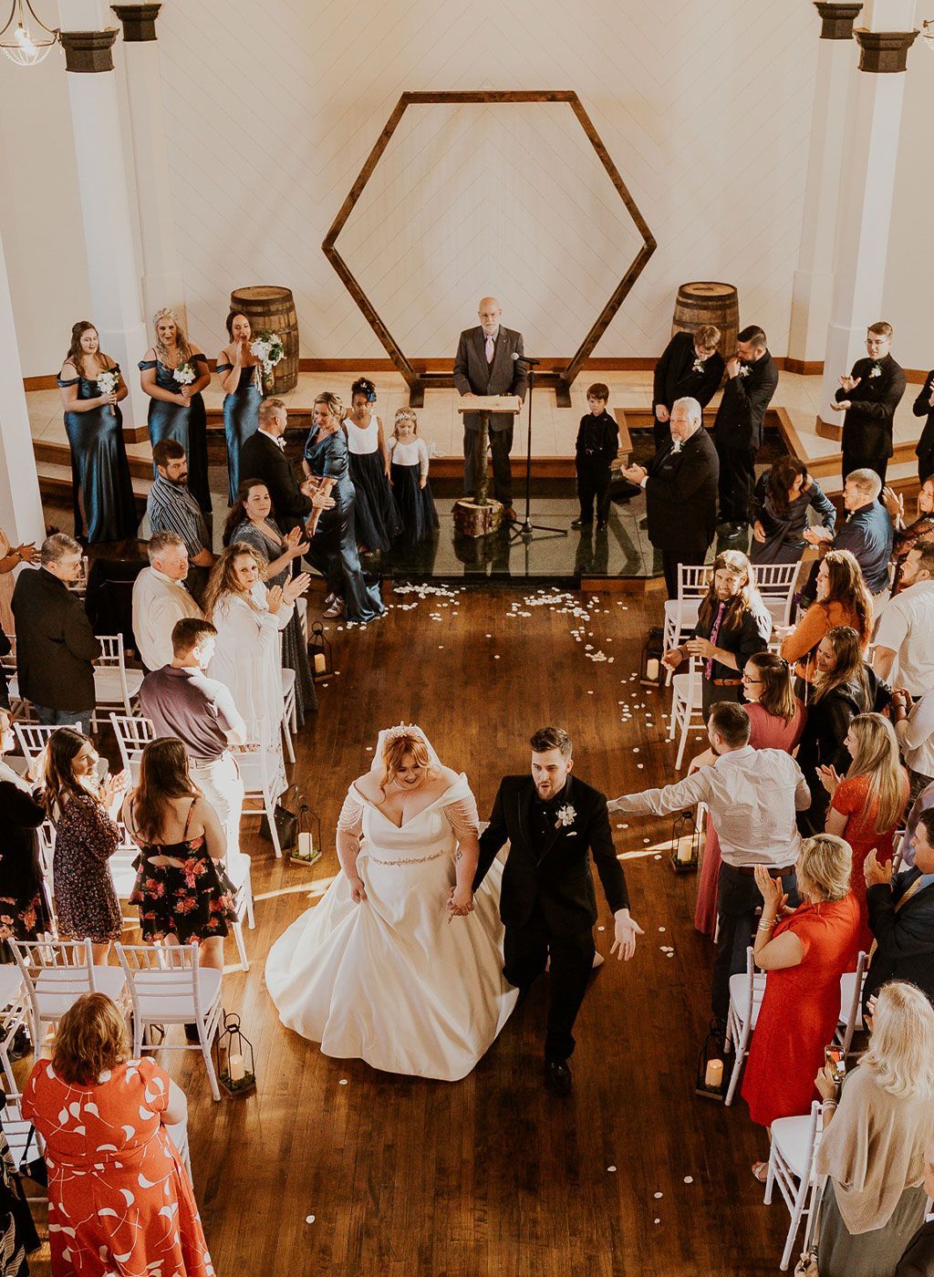 A bride and groom are walking down the aisle at their wedding reception.