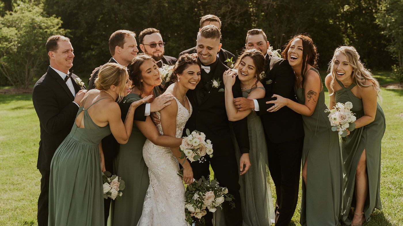 A bride and groom are posing for a picture with their wedding party.