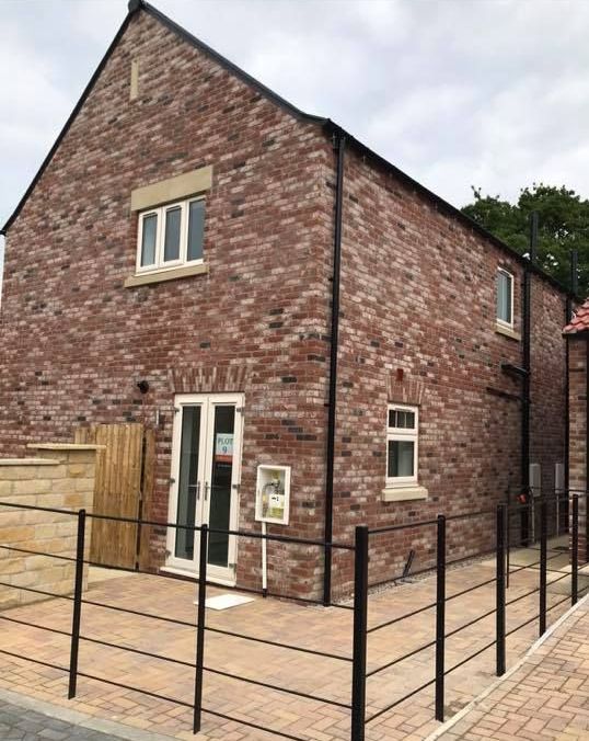 A brick house with a fence around it and a patio in front of it.