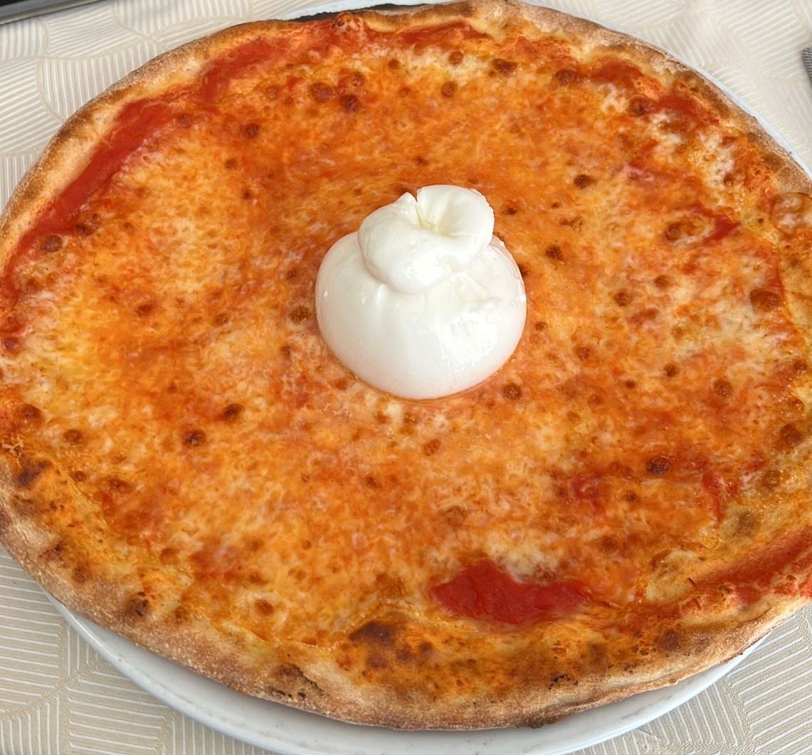 Pizza con mozzarella al centro su un piatto bianco.