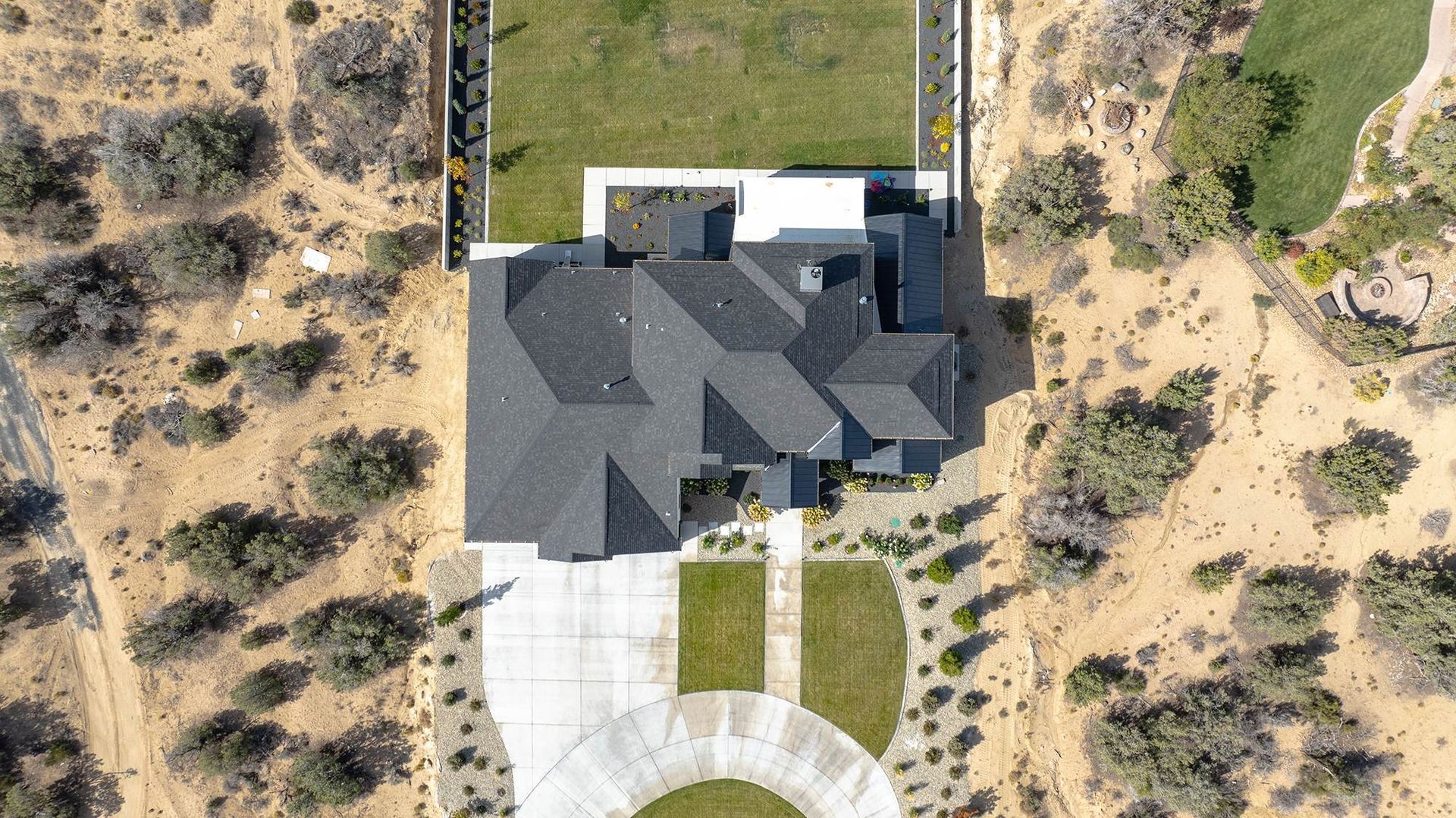 Top-down drone view of a complex black architectural shingle roof installation