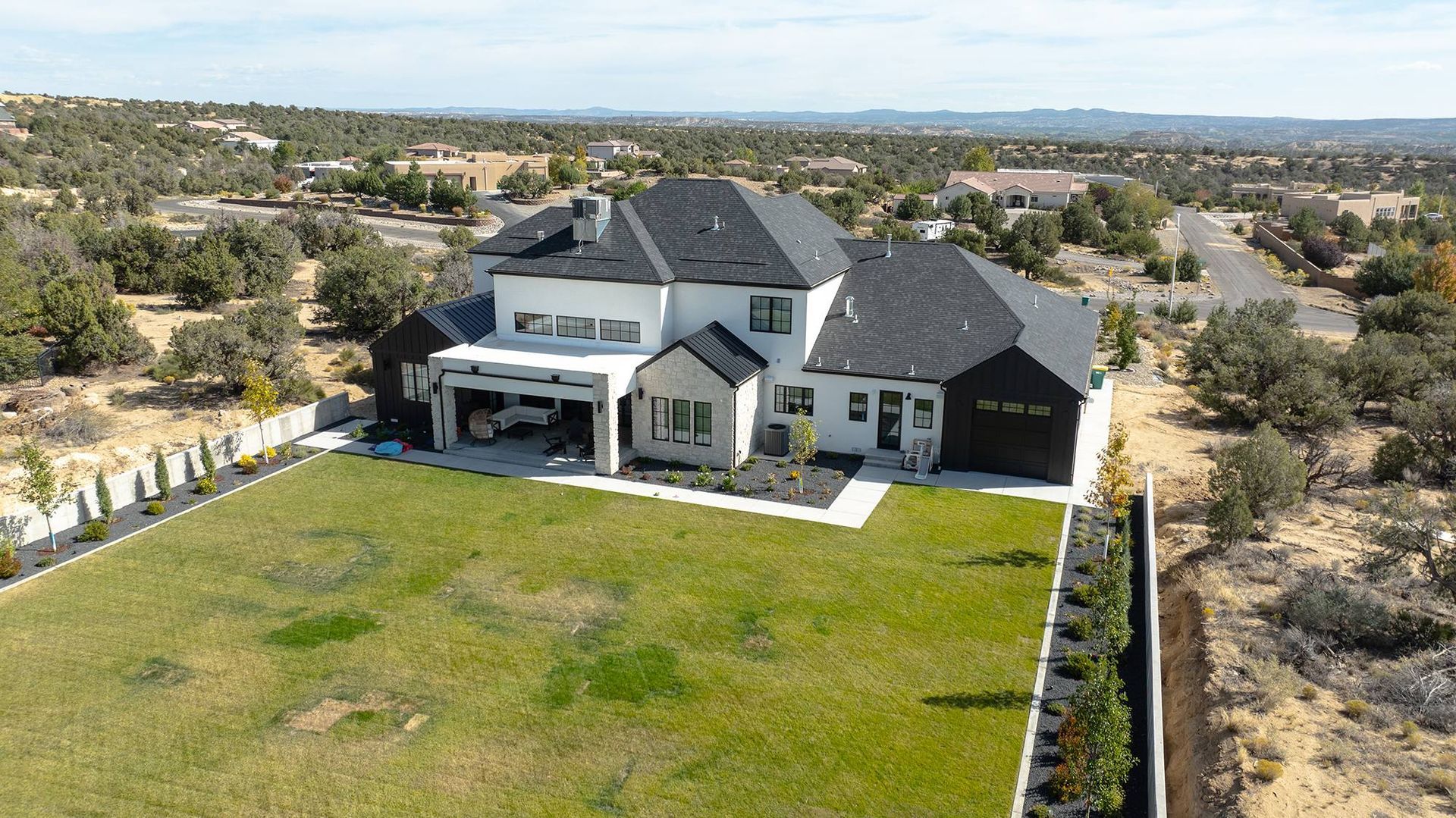 Rear aerial view showing the rooflines and transitions of a black architectural shingle roof