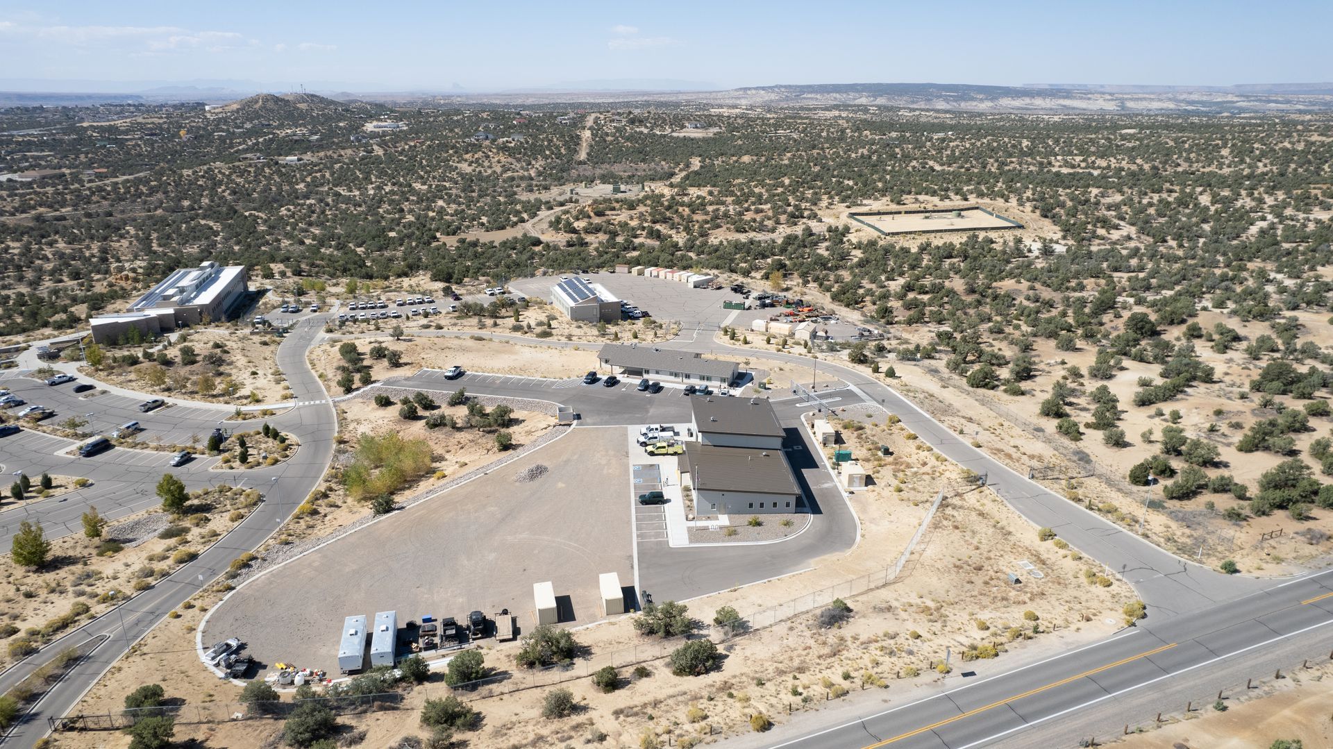 High aerial view of a fire station, surrounding access roads, gravel lot and desert vegetation.