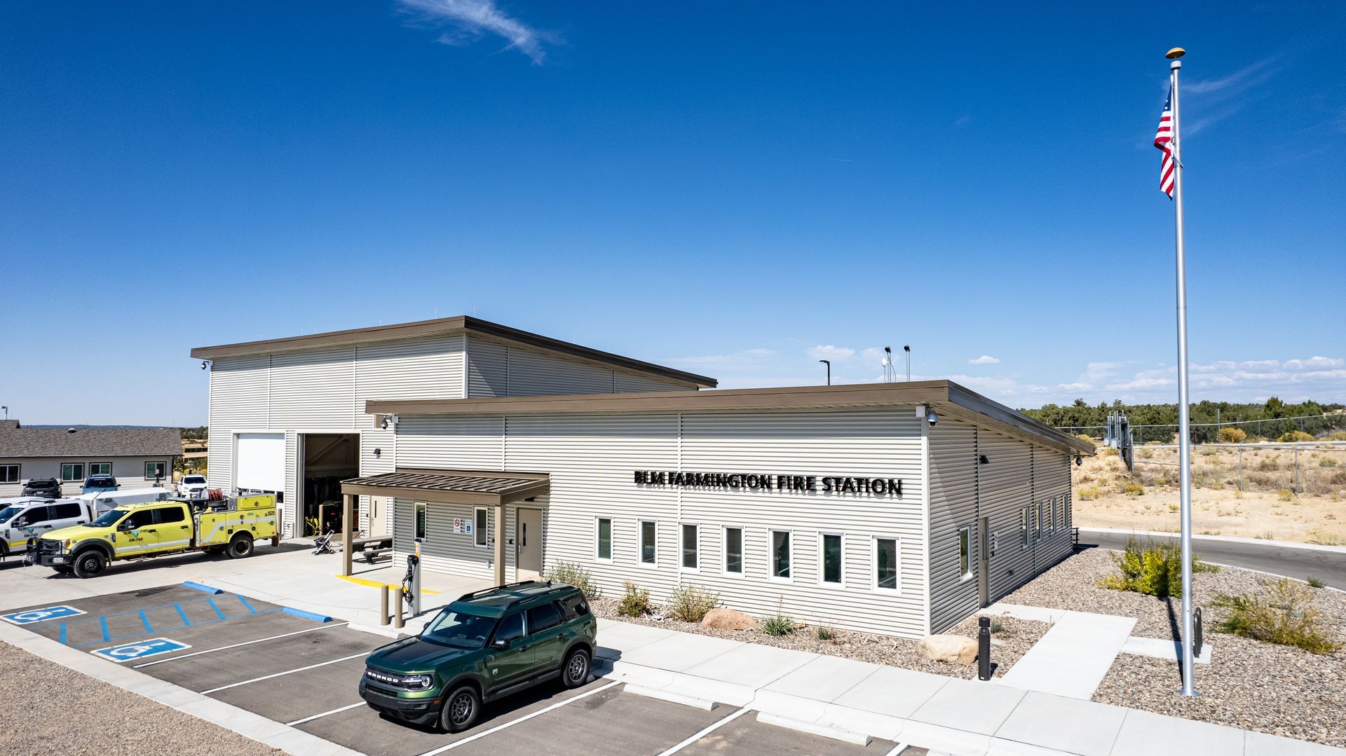 Front view of the San Juan County Fire Station with gray metal siding, a dark metal roof and parked vehicles.