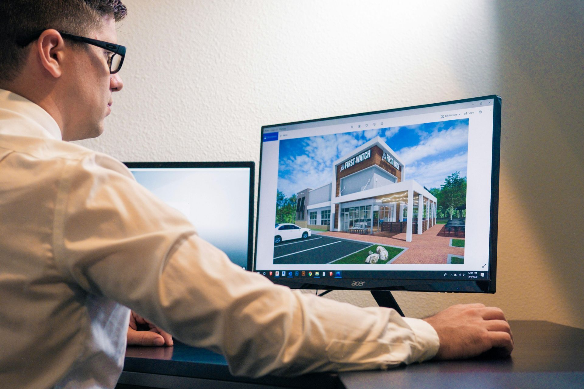 Person viewing a modern house design on a desktop monitor at a desk