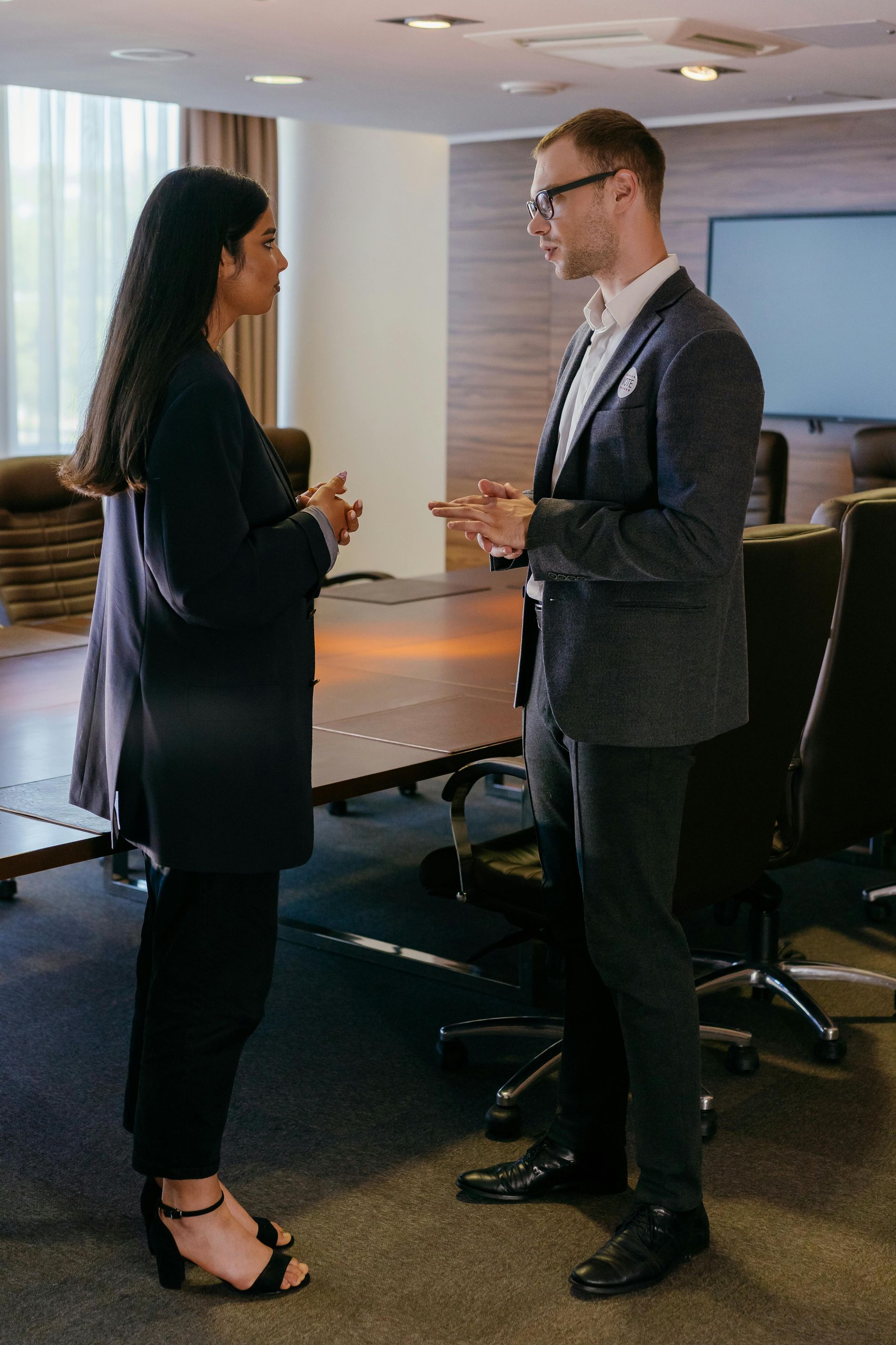 Two people standing and talking in an office conference room
