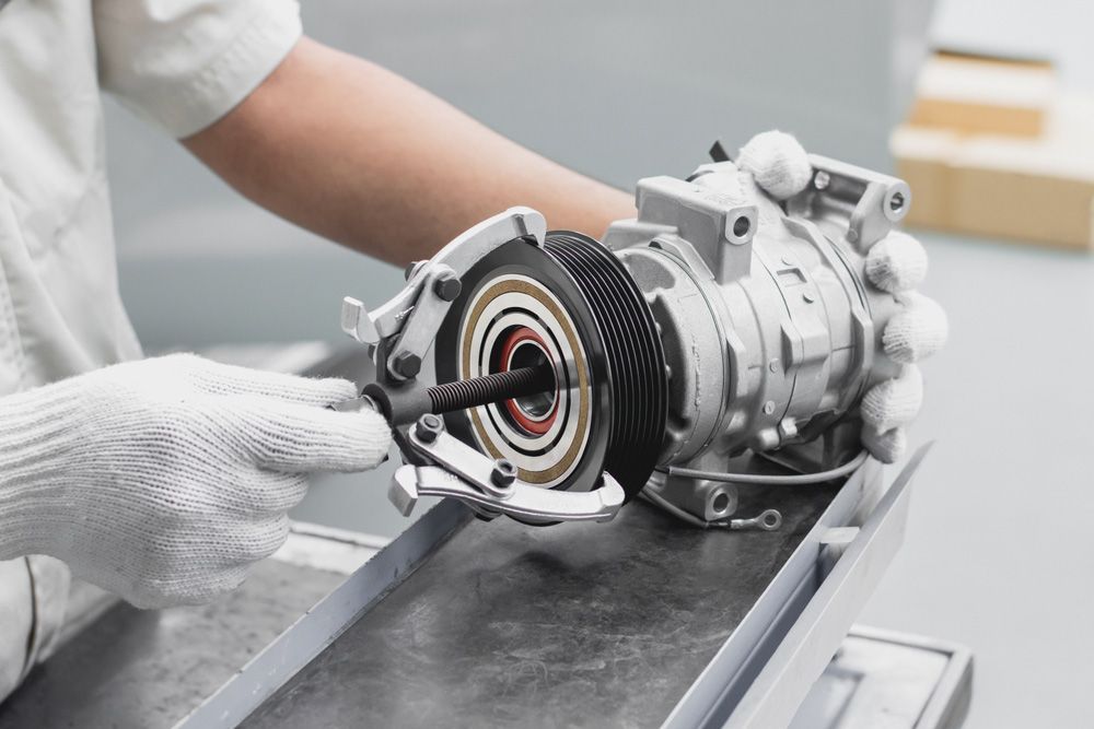A Person Is Working On A Car Air Conditioner Compressor — Airborne Auto Air in Gosford, NSW