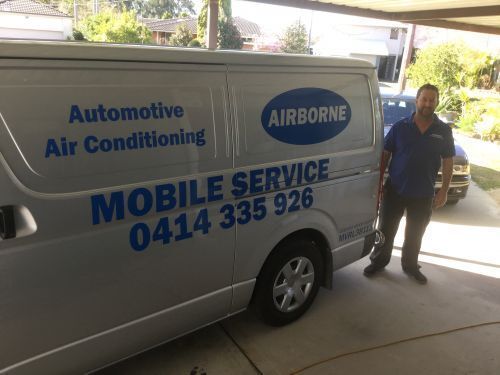 A Man Is Standing Next To A Mobile Service Van — Airborne Auto Air in Killarney Vale, NSW