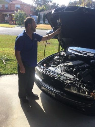A Man Is Looking Under The Hood Of A Car — Airborne Auto Air in Killarney Vale, NSW