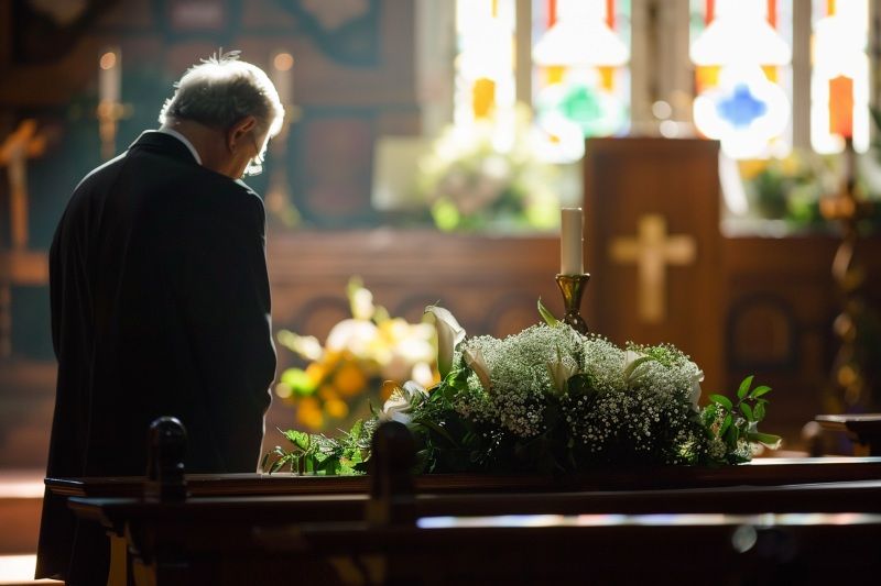 Mourner in chapel for Allentown, PA Traditional Funeral beside white flowers and candle