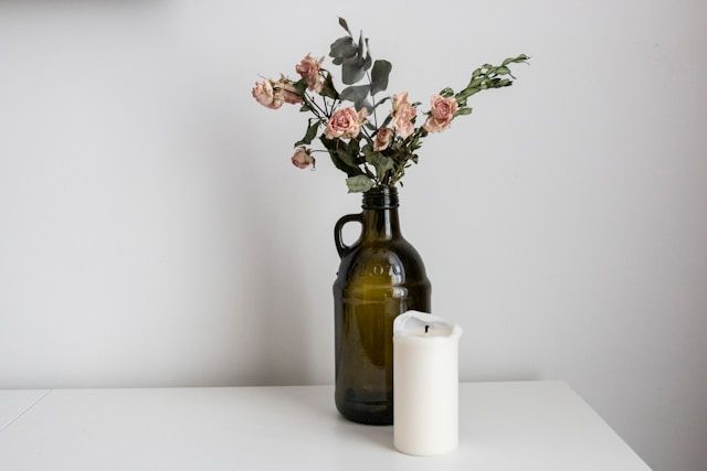 Simple vase with soft pink flowers beside white candle, cremation services Allentown, PA