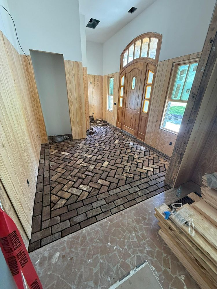 Entryway with brick floor, wood paneling, and a large wooden door. Construction in progress.