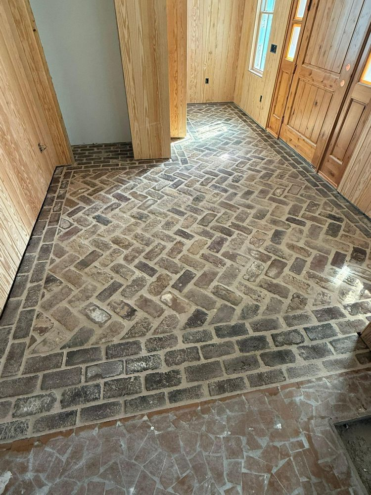 Brick floor hallway with herringbone pattern and border, leading to a wooden door.