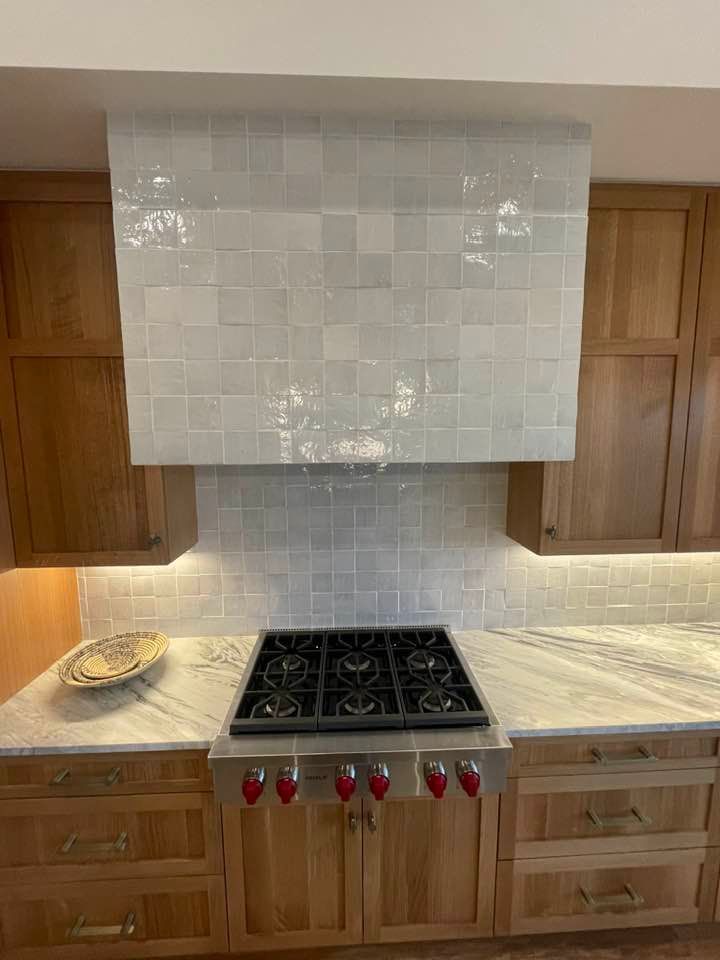 Kitchen with a gas stovetop, tile range hood, and wooden cabinets.