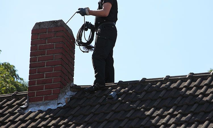 A person is cleaning a gutter with a high pressure washer.