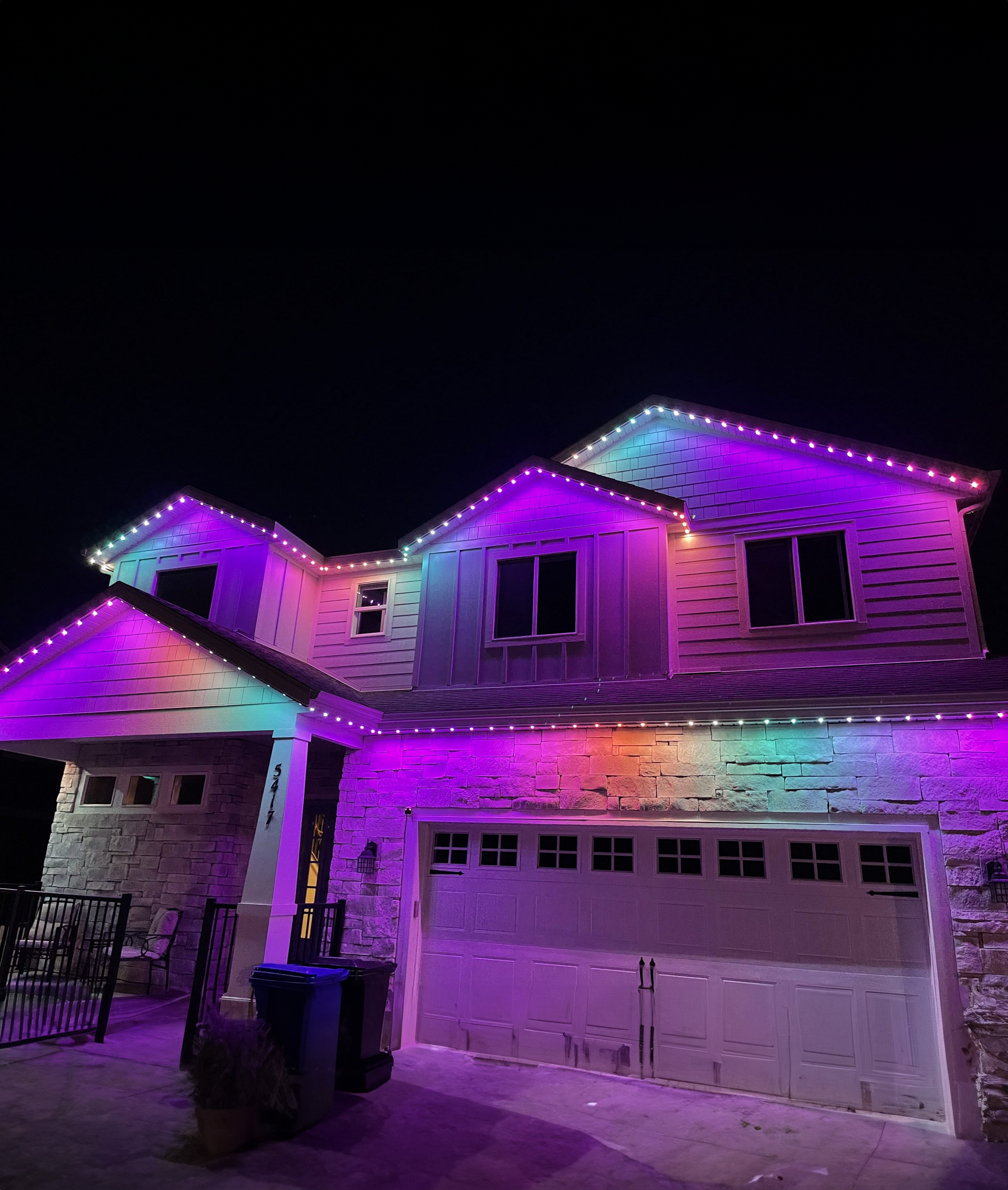 A house with purple and white lights on it at night.