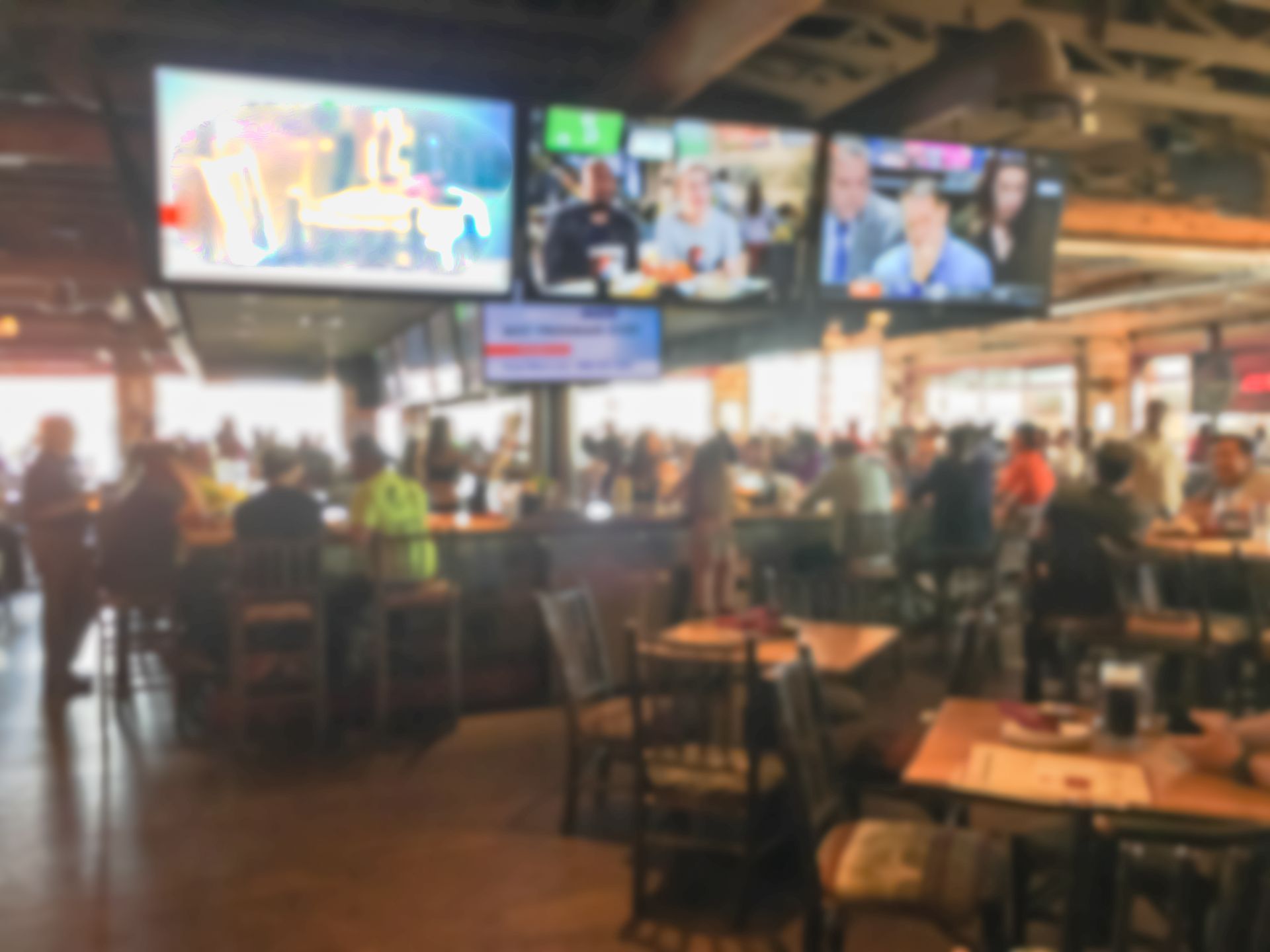 A blurry picture of a restaurant filled with people and televisions.