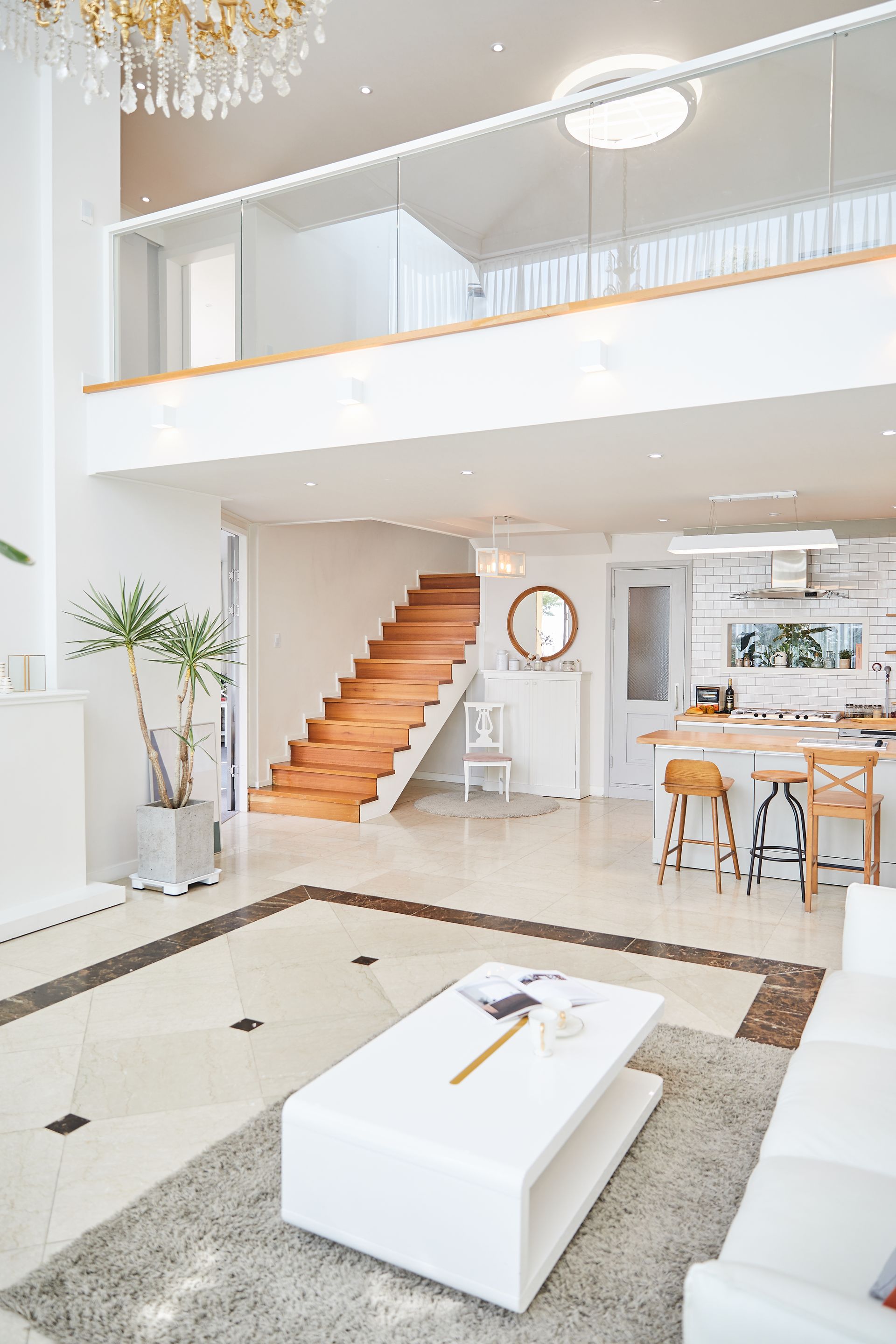 Salon moderne avec canapé d'angle, escalier en bois et coin repas. Couleurs neutres.