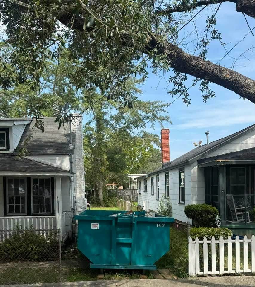 Teal Dumpster Dynasty 15-yard roll-off dumpster placed between two older homes – dumpster rental in Andrews, SC