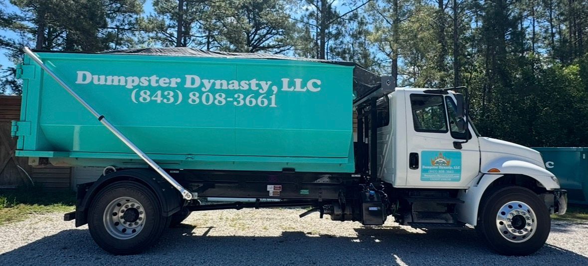 Green dumpster truck with “Dumpster Dynasty, LLC” logo parked outdoors on a sunny day