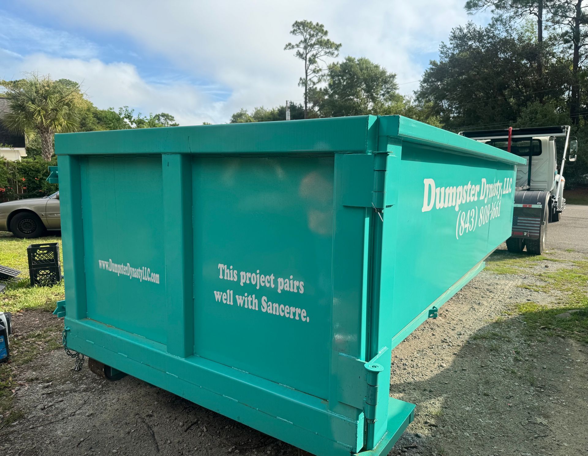 Turquoise donation dumpster outdoors with white lettering on its side