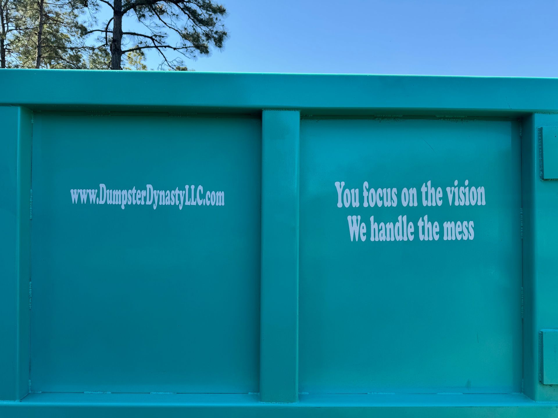 Teal wall with white text reading “You focus on the vision / We handle the mess”