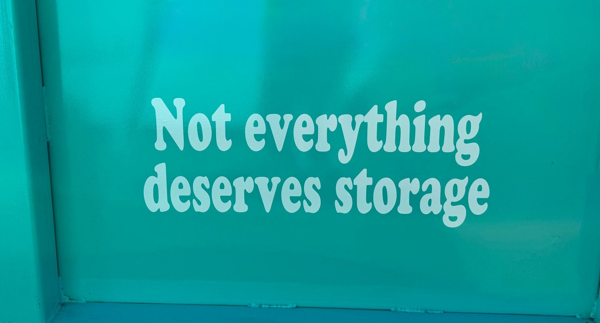 Turquoise wall with white text reading, “Not everything deserves storage.”