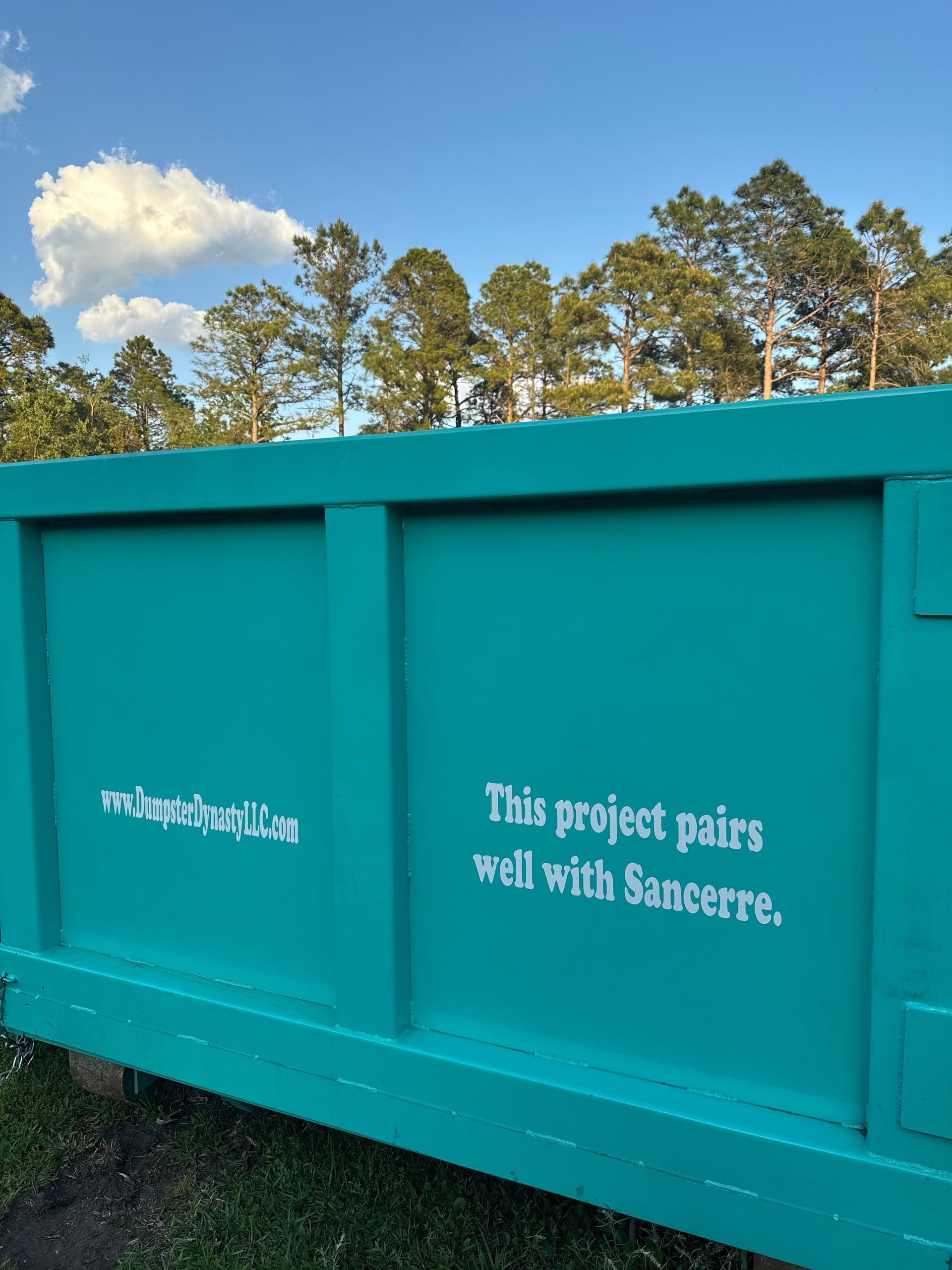 Turquoise dumpster with white text reading “This project pairs well with Sincere.” under a blue sky