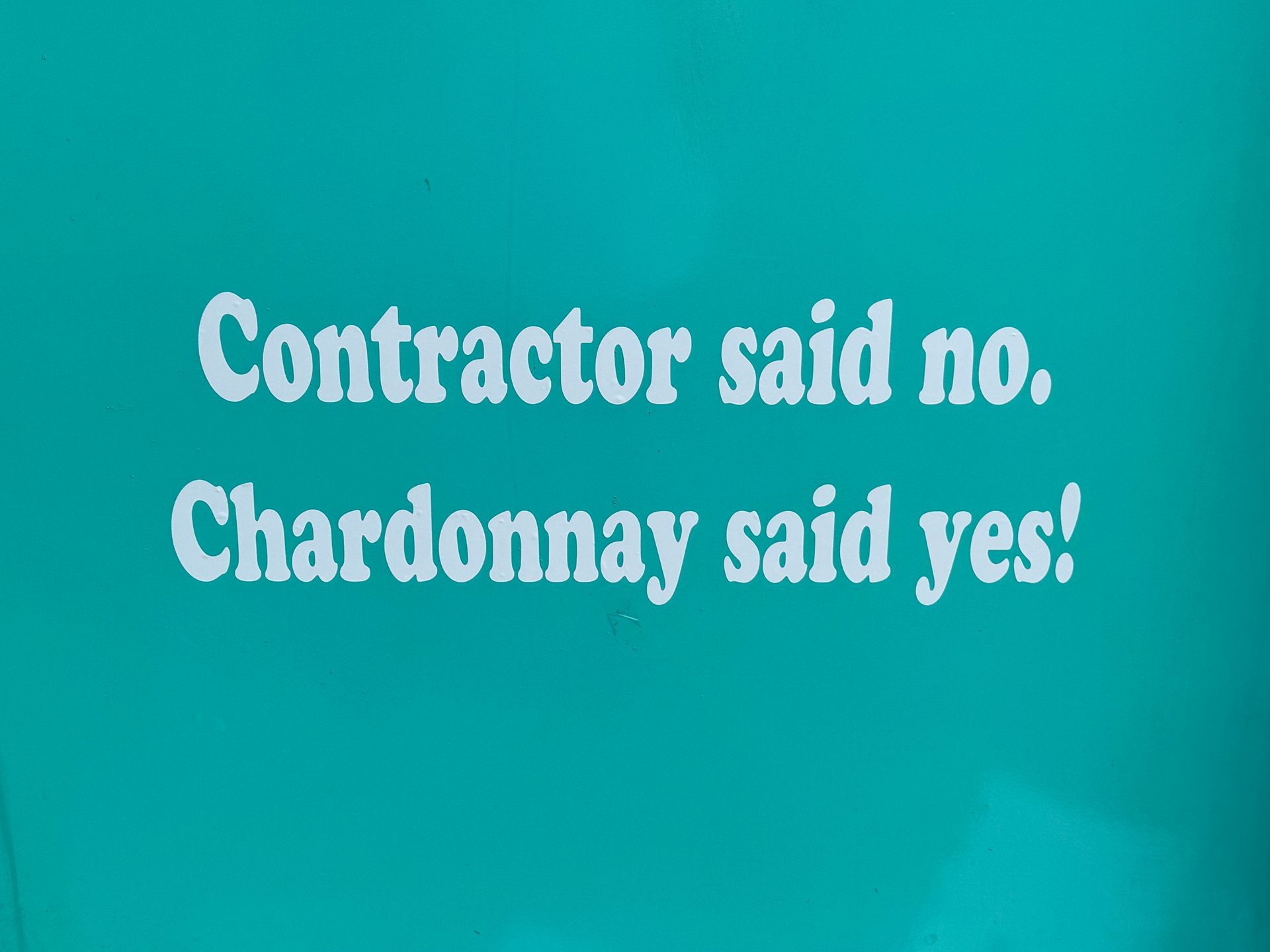 Turquoise sign with white text: “Contractor said no. Chardonnay said yes!”