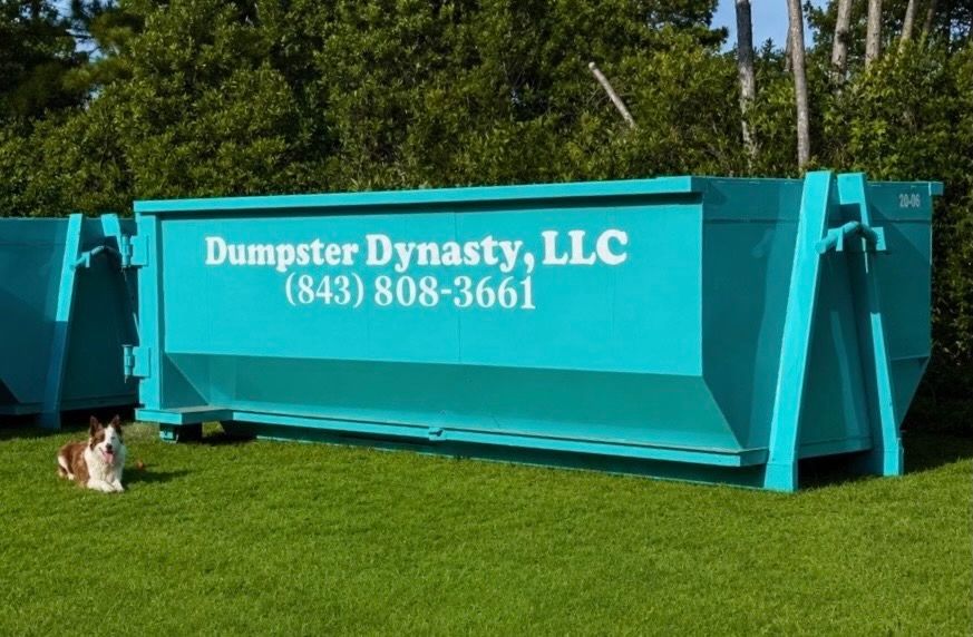 Turquoise Dumpster Dynasty LLC dumpster on grass with phone number printed on the side