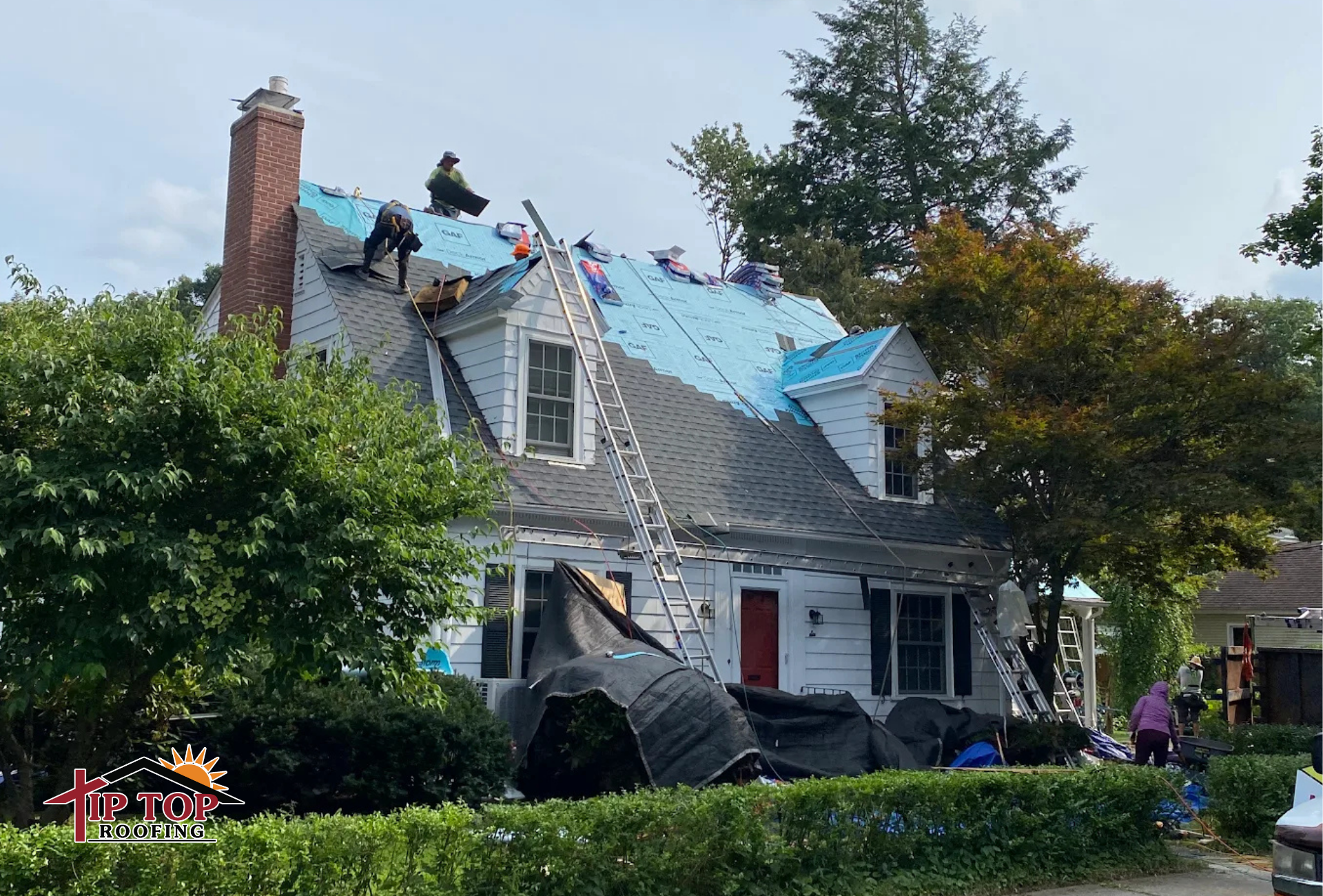 Tip Top Roofing crew mid installation on a residential home with protective tarps in place