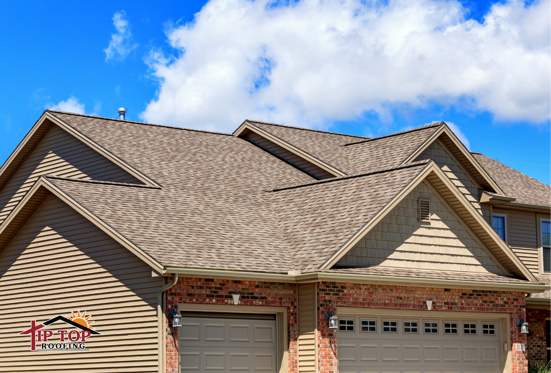 A residential home with an architectural shingle roof against a bright blue sky.