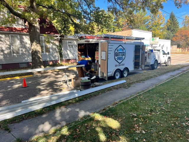 White utility trailer with an open side hatch parked by a sidewalk in a tree-lined park.
