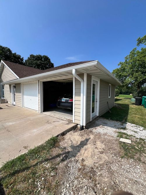 Single-car garage with open door beside a driveway, viewed on a sunny day.