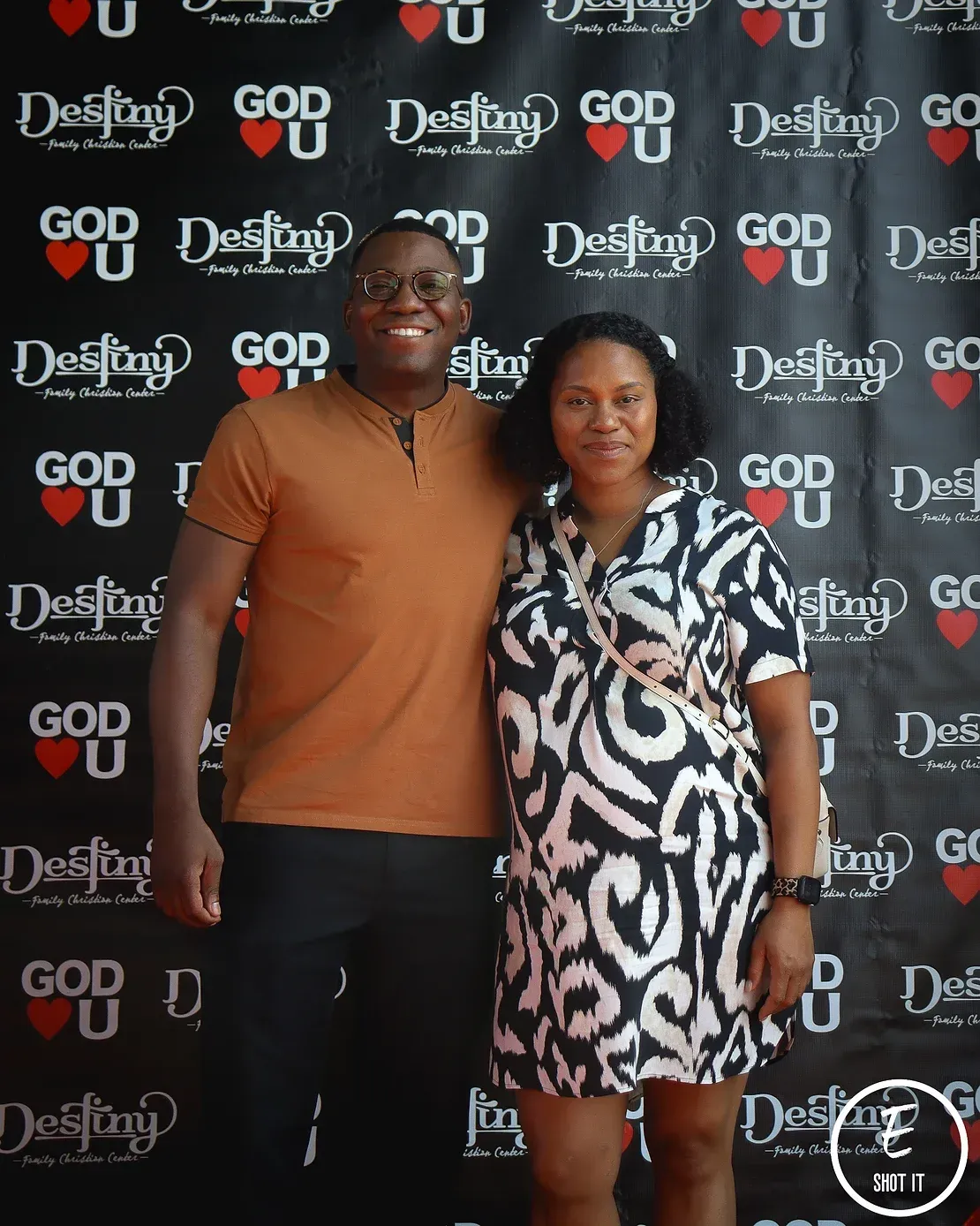 A man and a woman are posing for a picture in front of a wall that says god destiny