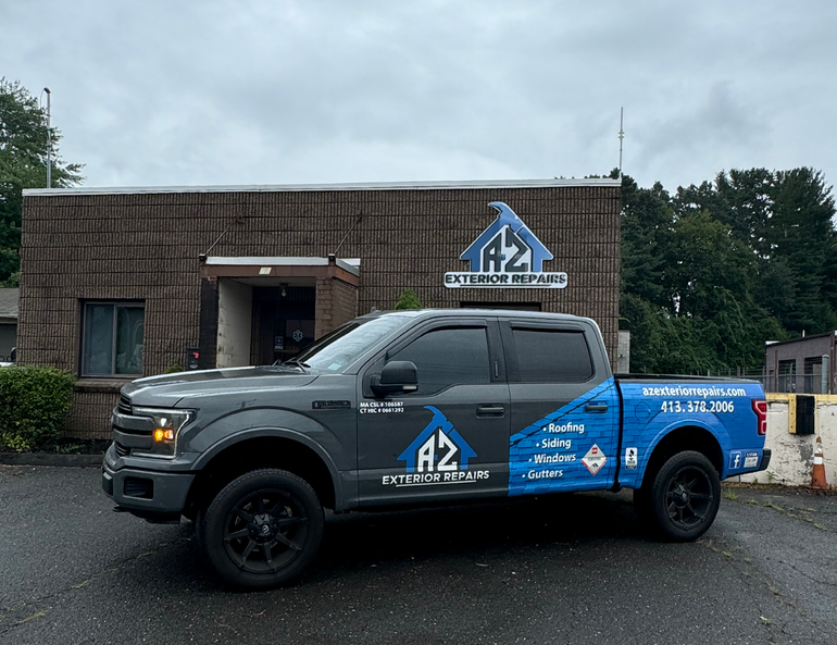 A grey pickup truck parked in front of a brick building featuring the