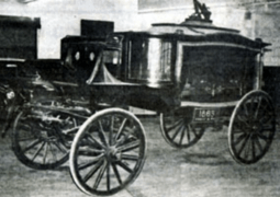 A black and white photo of an old horse drawn carriage
