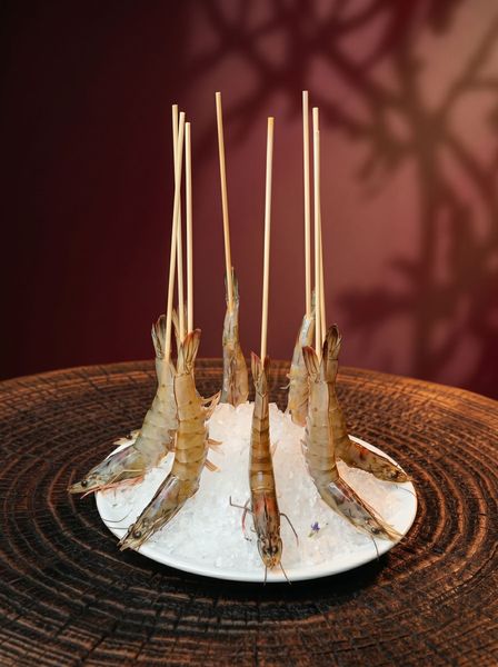 White plated dessert topped with five caramelized spikes on a woven brown surface against a red background