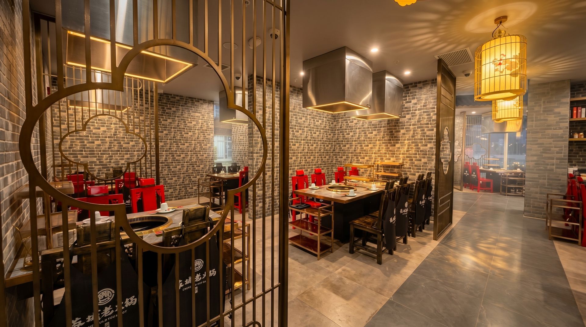 Elegant restaurant dining area with red table settings, warm lantern lighting, and decorative stone walls