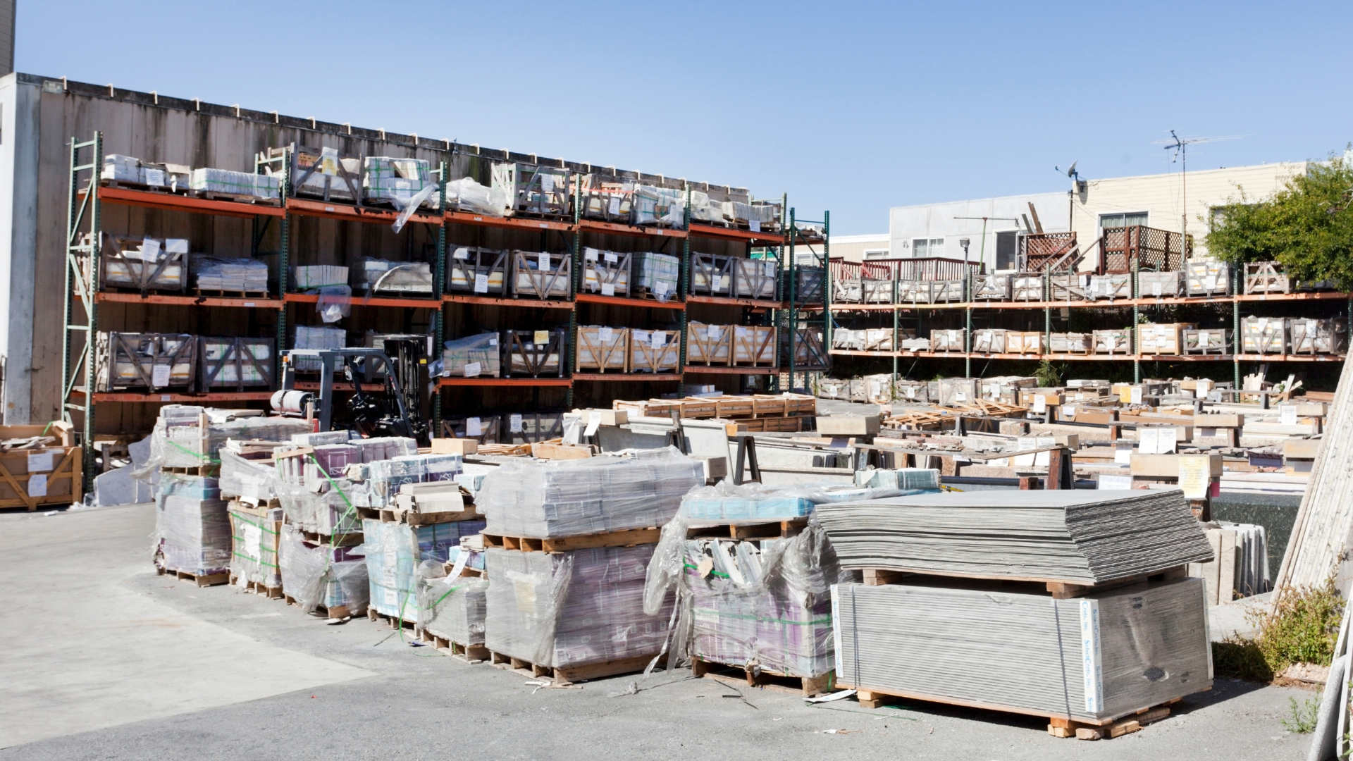 Outdoor storage of building materials on pallets and shelves.