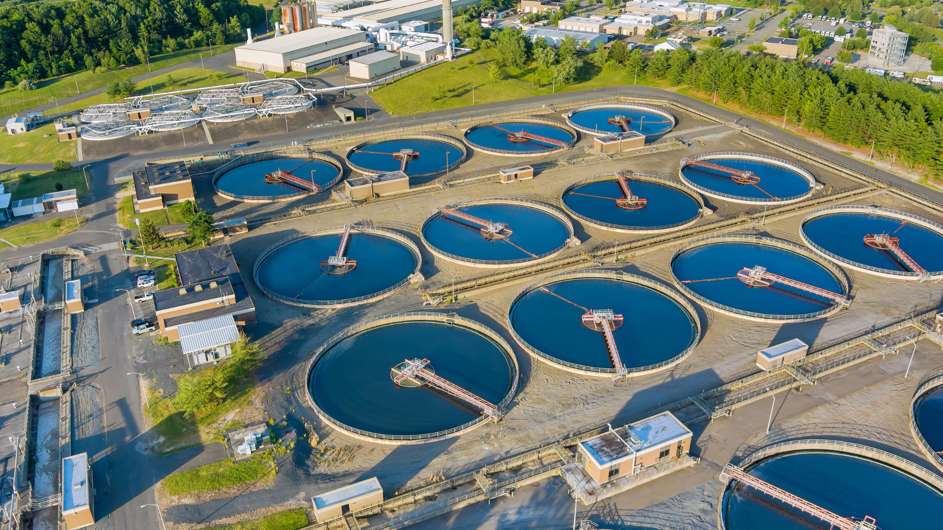 Aerial view of a wastewater treatment plant with several large circular tanks.