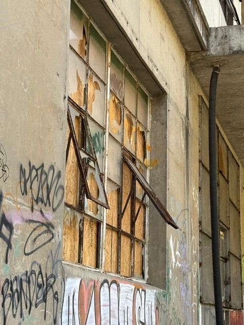 Graffiti-covered building with broken windows boarded up with wood; exterior view.