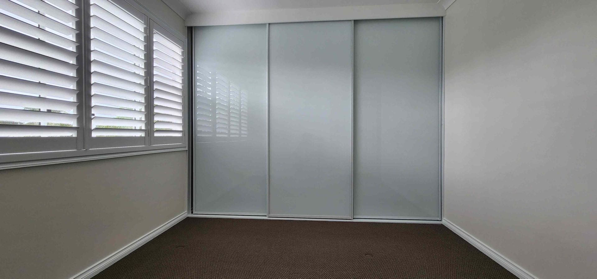 Empty Bedroom With Closed Sliding Wardrobe — Port Blinds & Awnings in Port Macquarie, NSW