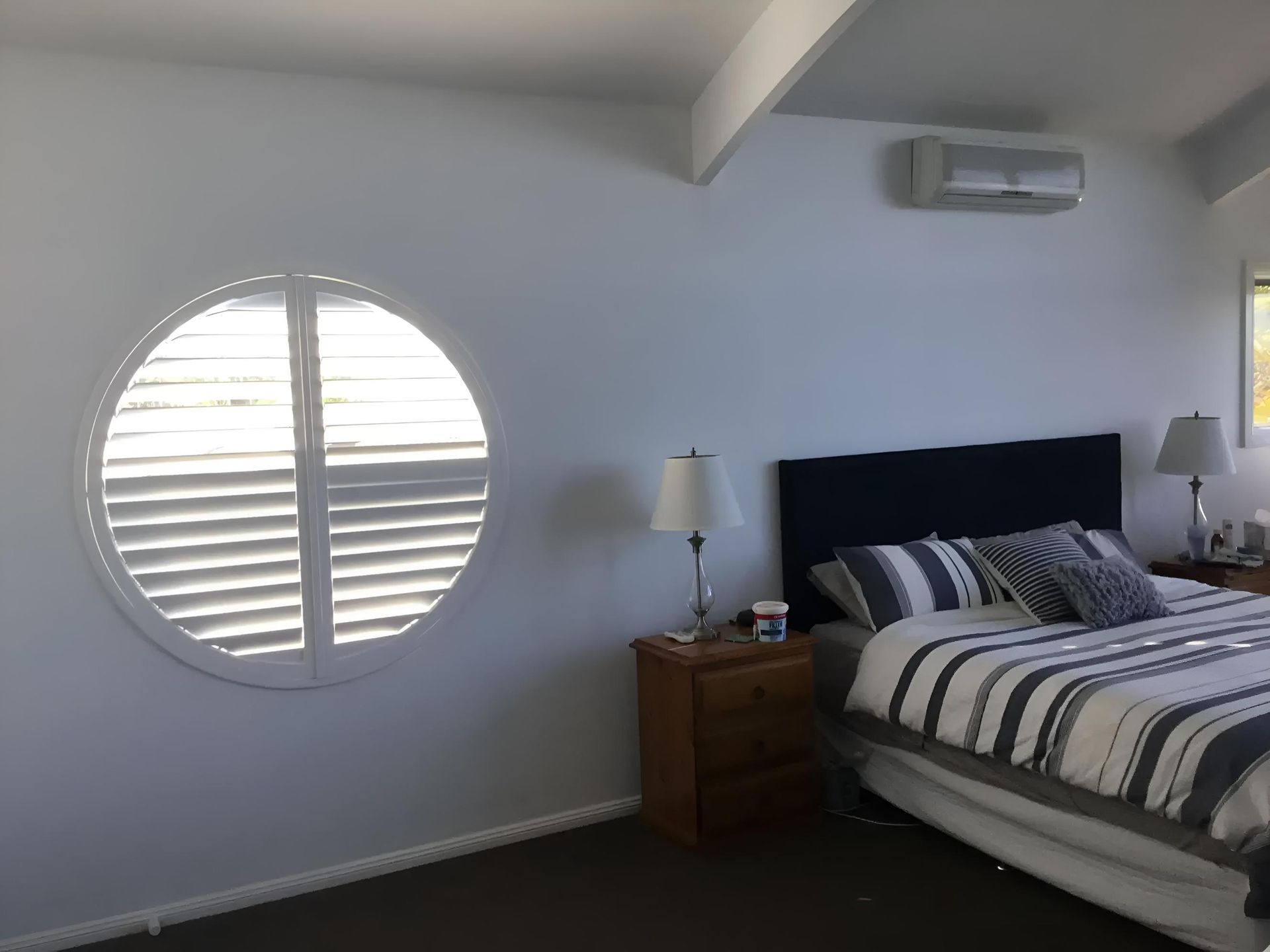 A Bedroom With a Round Window and a Bed — Port Blinds & Awnings In Nambucca Heads, NSW