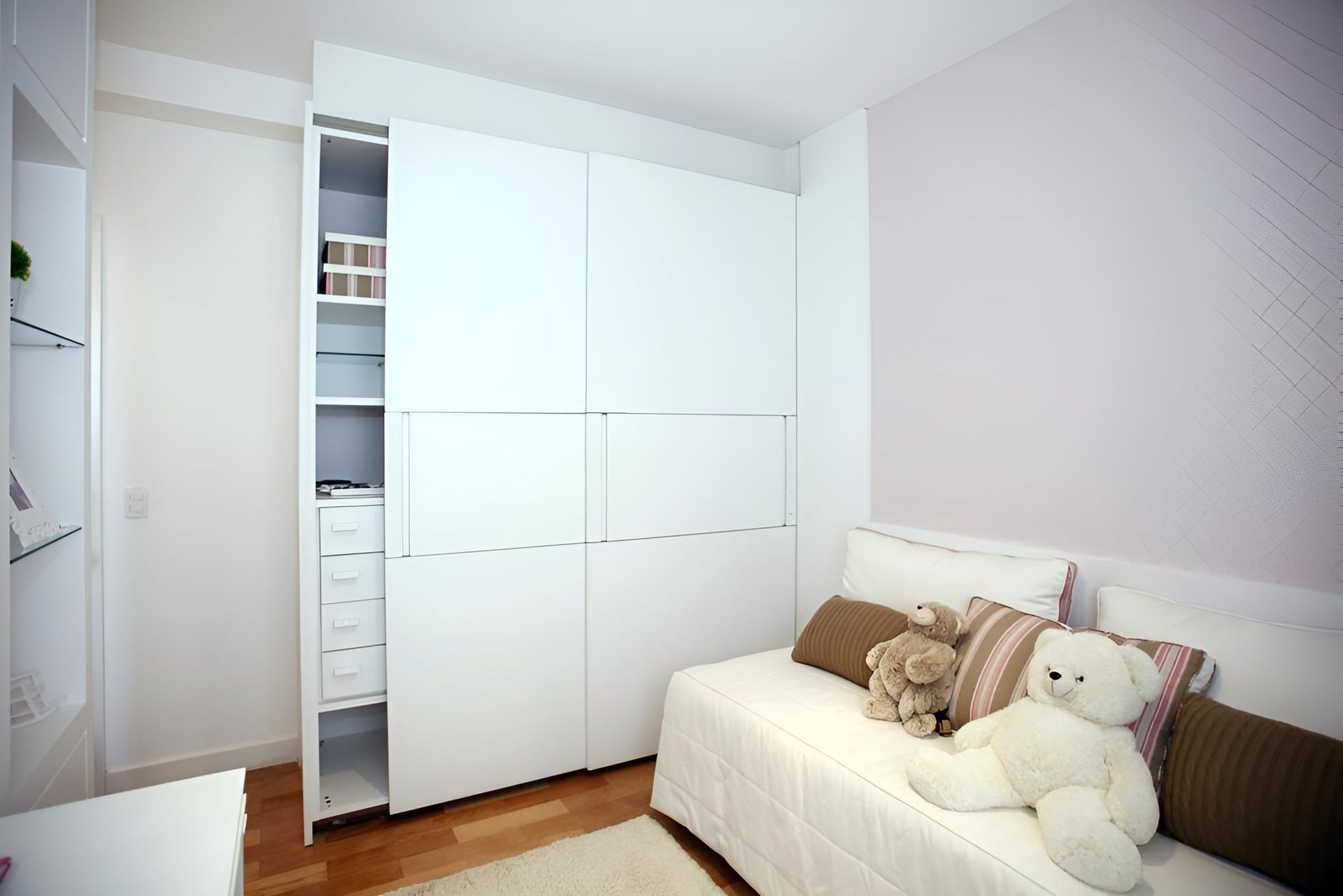 Bright bedroom with white wardrobe, open shelves, and a couch with stuffed animals. — Port Blinds & Awnings in Port Macquarie, NSW