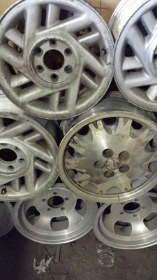 A pile of aluminum wheels are stacked on top of each other.