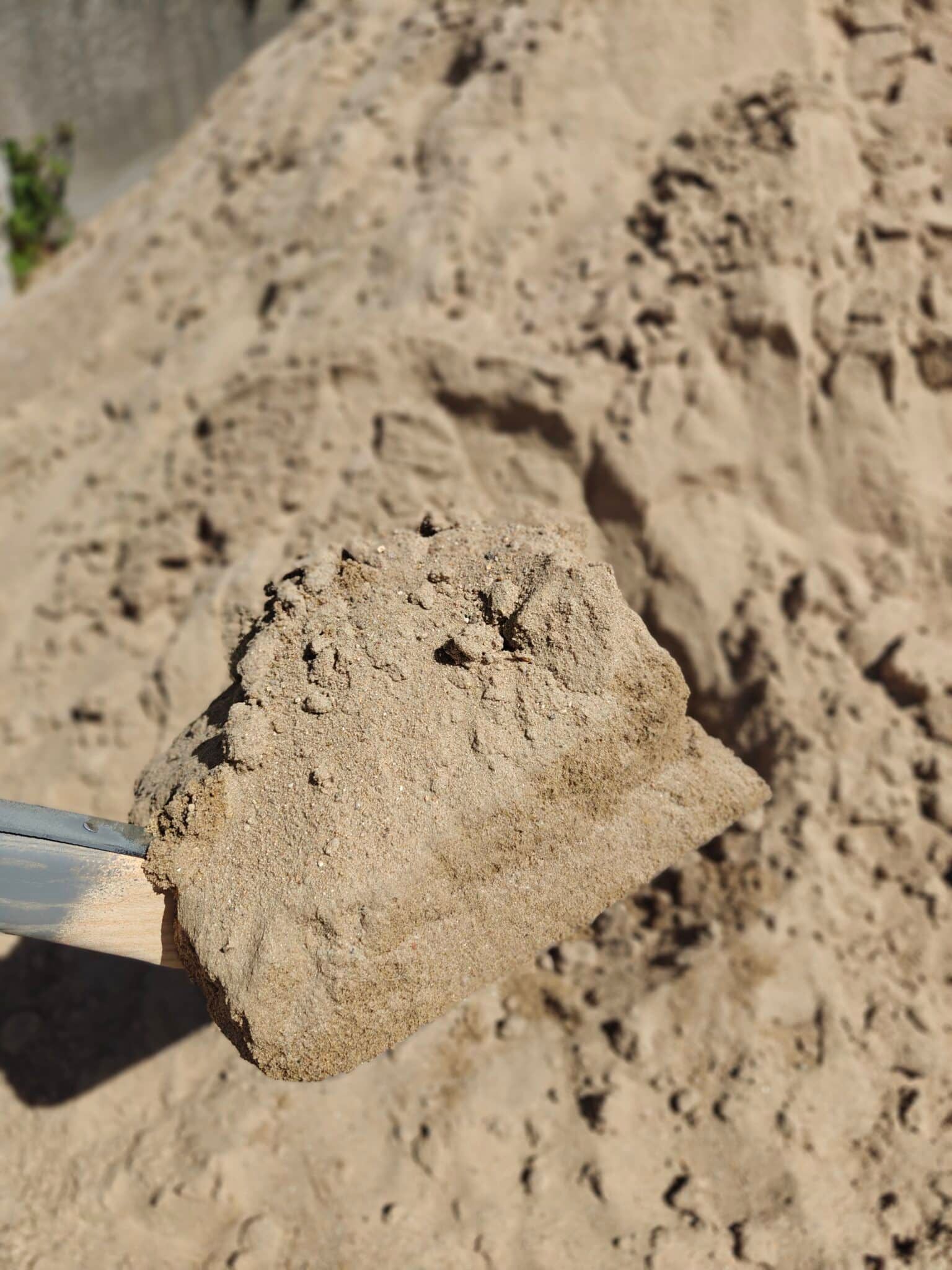 Hånd der holder en lille sandsten eller klump over en bunke sand