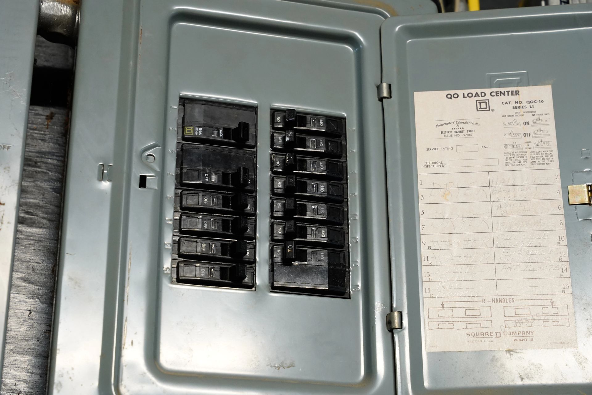 An open electrical breaker panel with a door and a handwritten index label on the inside.
