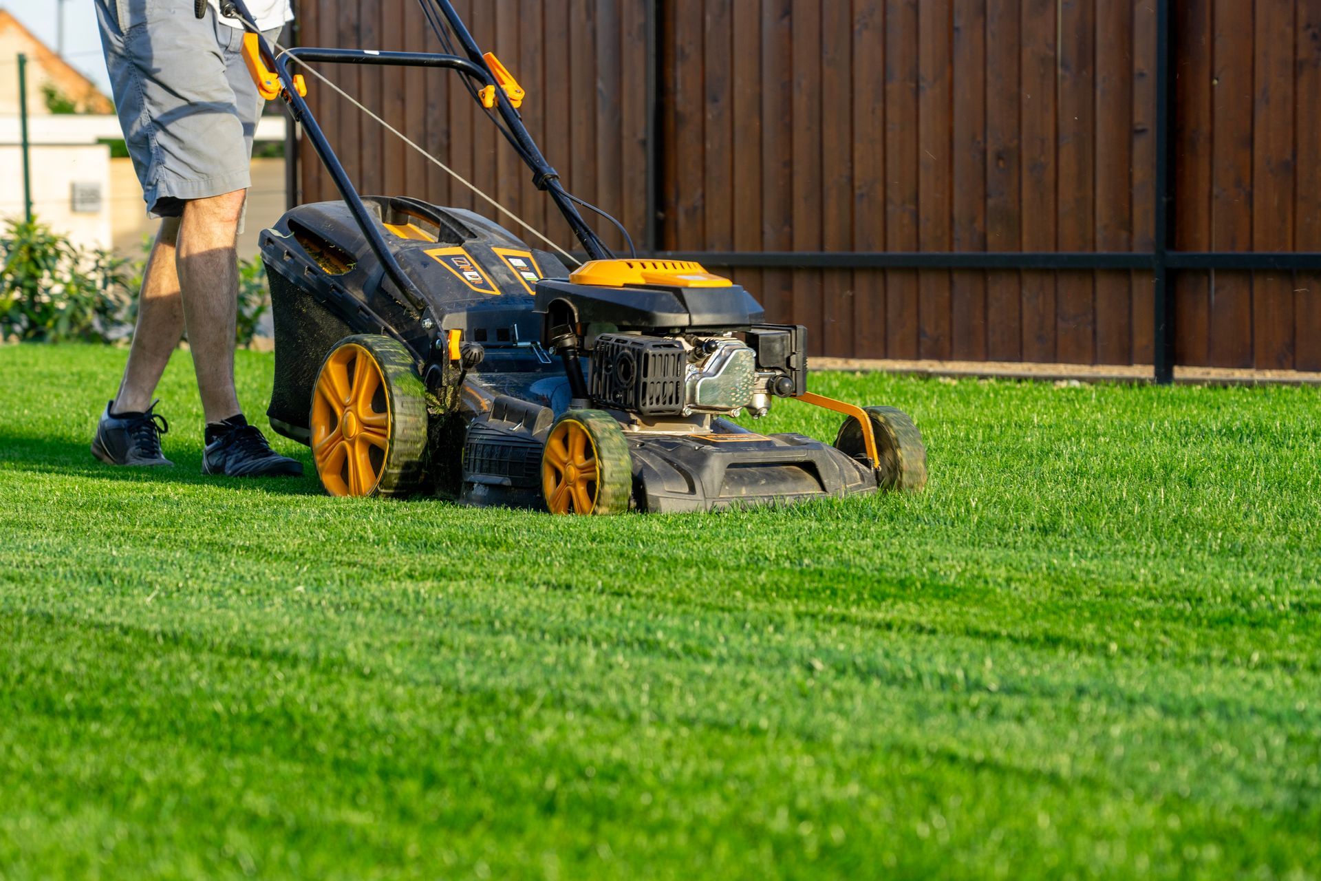 A man is mowing a lush green lawn with a lawn mower.